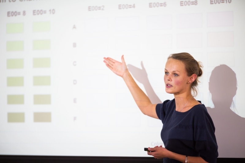 A woman presenting to an audience after using speechwriting services from SpeechPower